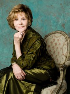 Photo of Glorya Kaufman sitting on a chair wearing a green dress