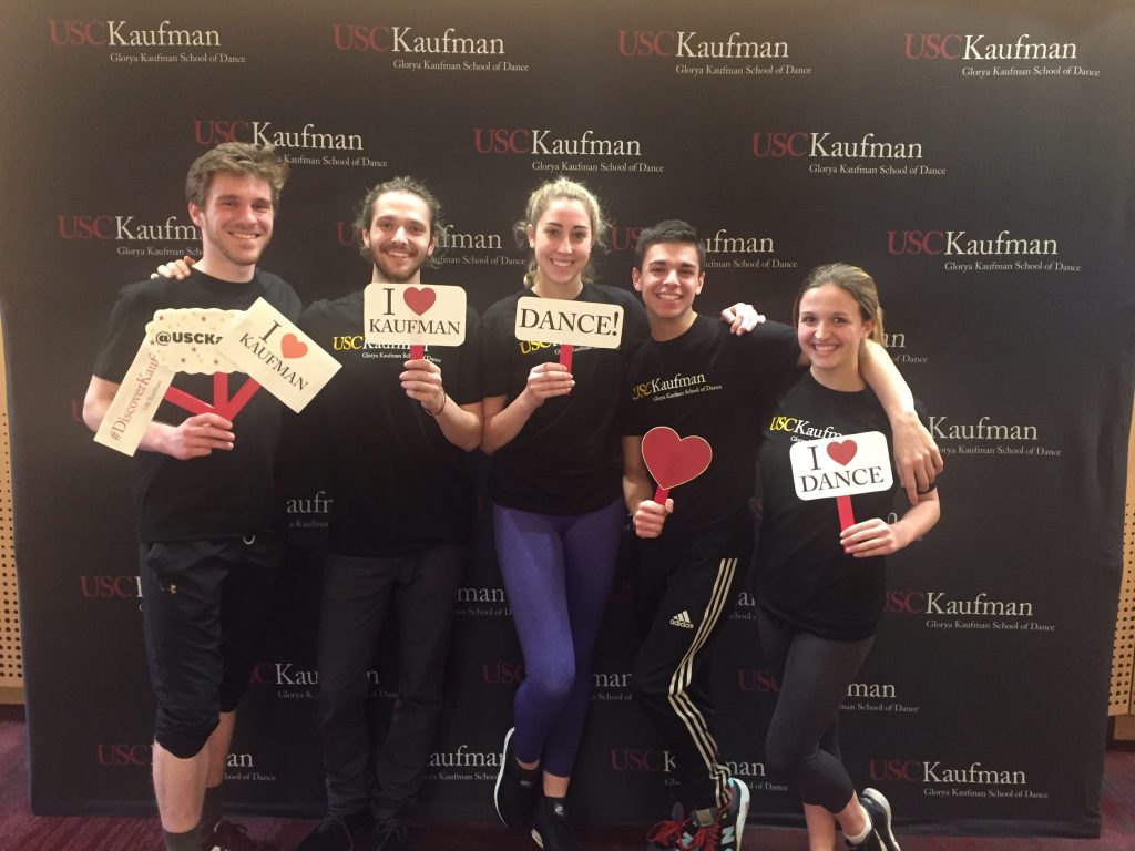 five students smile holding signs