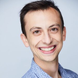 close up of a guy with short hair wearing a blue button down