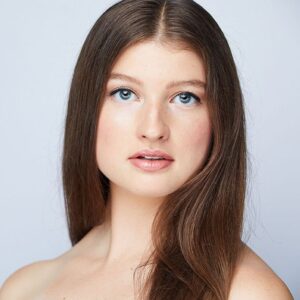 close up of a girl with long brown hair and blue eyes