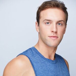 close up of a guy with short blonde hair wearing a blue tank