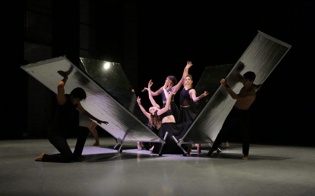 Dancers hold angular poses as a box of mirrors is dismantled around them.