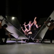 Dancers hold angular poses as a box of mirrors is dismantled around them.