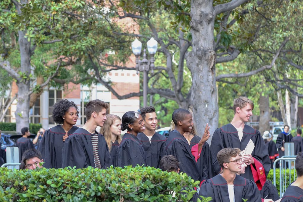 A group of students in black convocation robes pose for a group picture