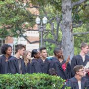 A group of students in black convocation robes pose for a group picture