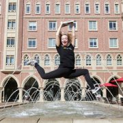 Girl jumps with her arms in the air in front of a water feature in the USC Village
