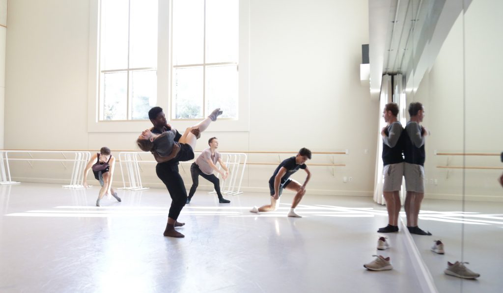 Dancers in a studio with choreographer at the front, directing.