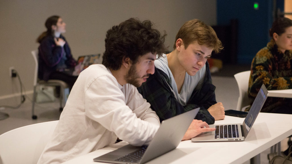 Two students at a desk looking at laptops