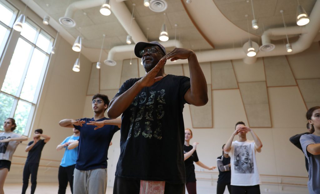 Teacher demonstrating steps in front of students in dance studio.