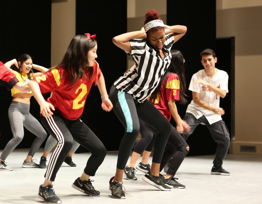 Students in sports jerseys perform at a hip-hop showcase.