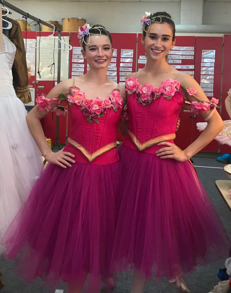 two women standing with hands on their hips wearing pink costumes from The Nutcracker