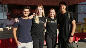 four students smile in front of an In-N-Out burger truck