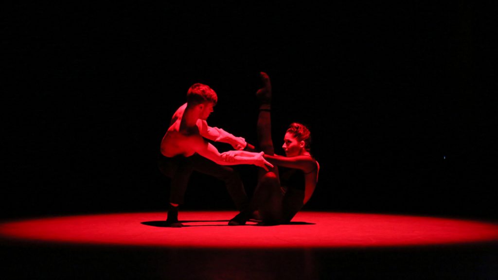 Man and woman dancing under red light.