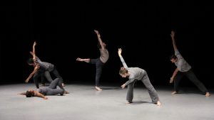 dancers wearing gray perform on stage