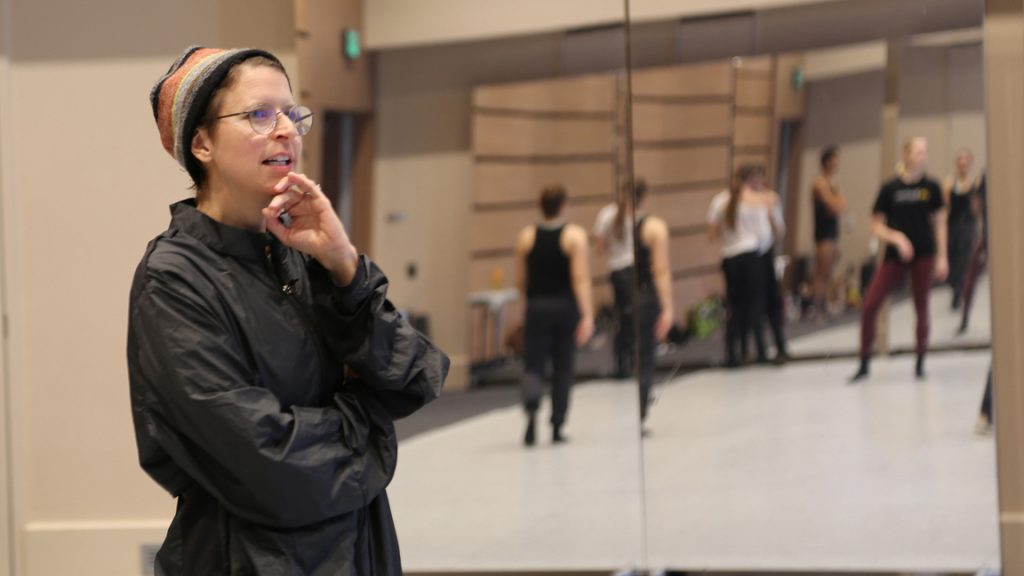 Woman with glasses watching dancers rehearse