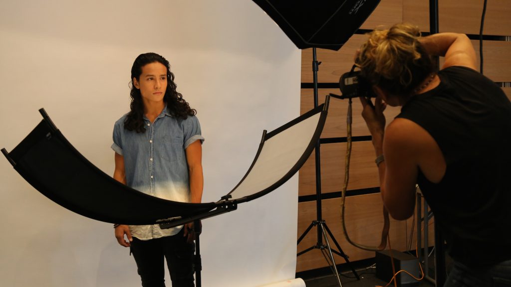 Photographer taking headshots with senior in front of white backdrop