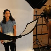 Photographer taking headshots with senior in front of white backdrop