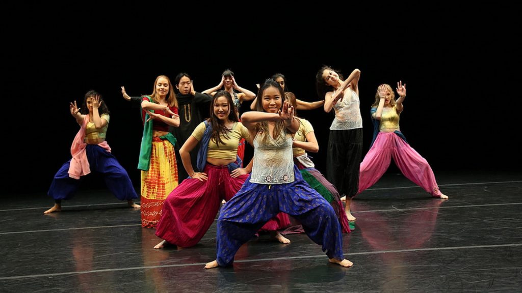 Dançarinos coloridos, calças bater uma pose no palco