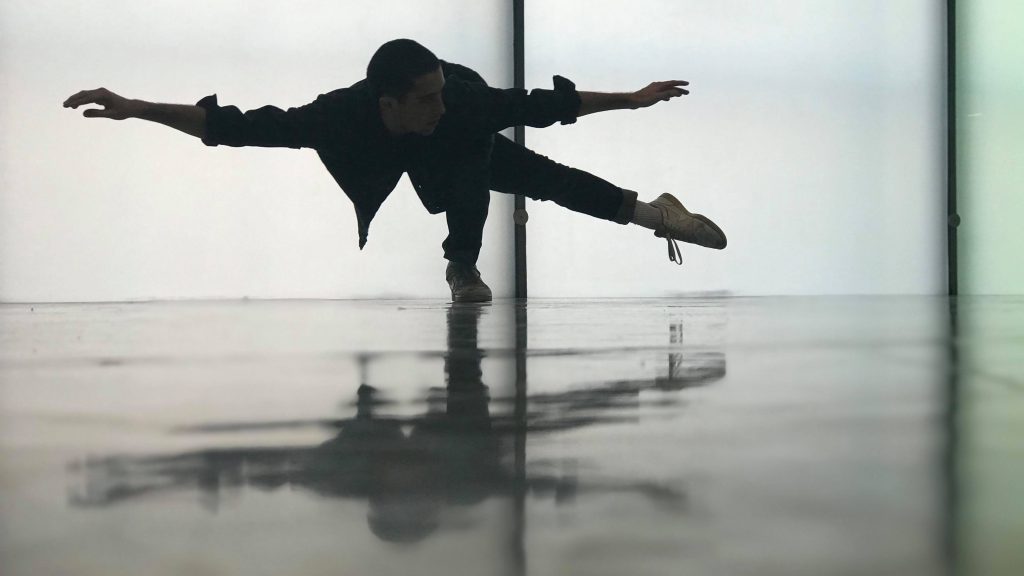 boy dancing in front of opaque window