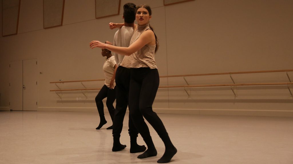 dancers wearing black pants and light tops in studio