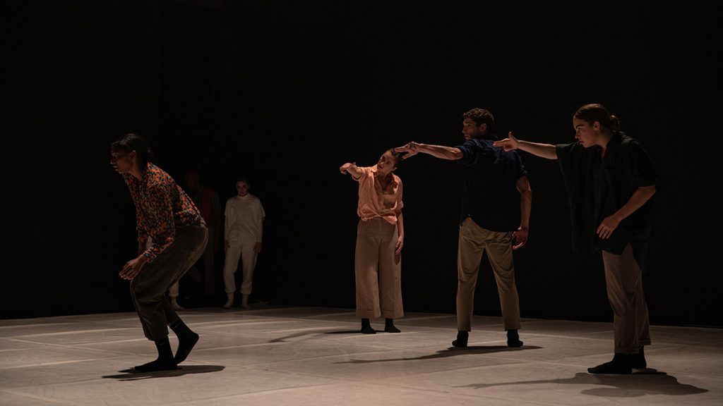 three dancers pointing to another on stage