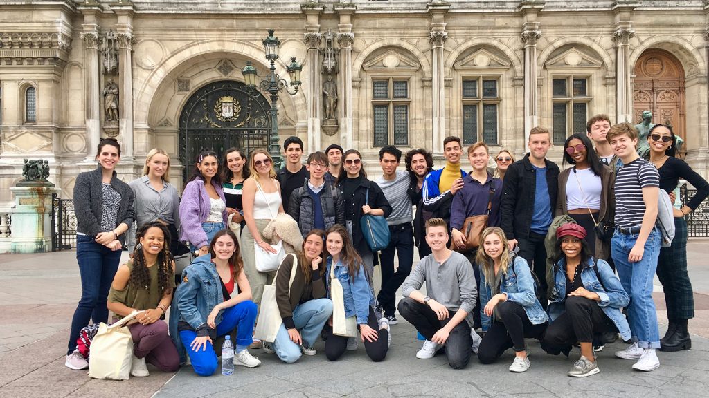 two lines of people stand in front of a French hotel