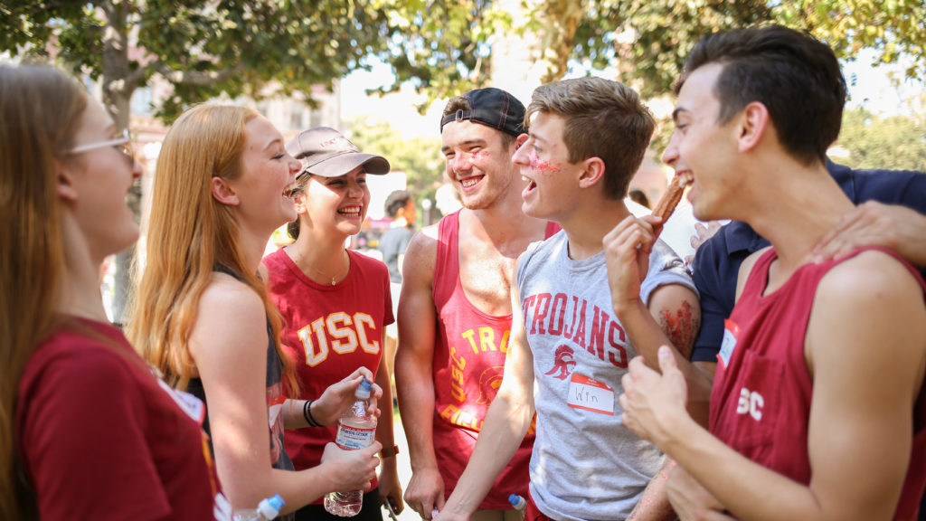 Students laughing and smiling in USC colored clothes