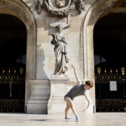 Win McCain wearing gray unitard and white socks posing in front of French building