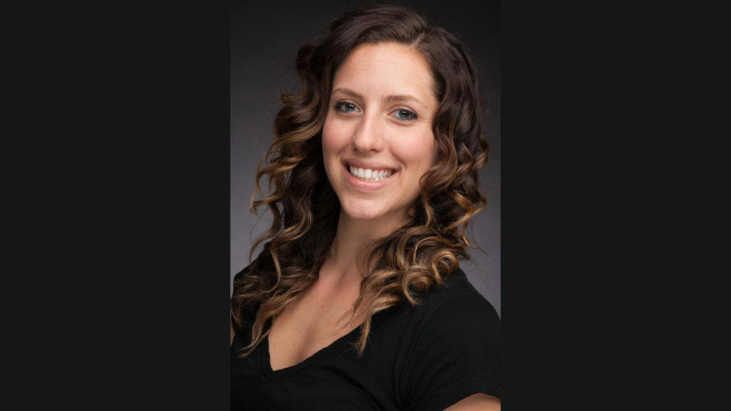 Marisa, wearing a black t-shirt smiles at the camera.