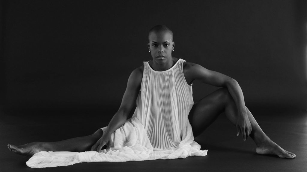 black and white photo of Hope Boykin sitting on the floor wearing a long white dress