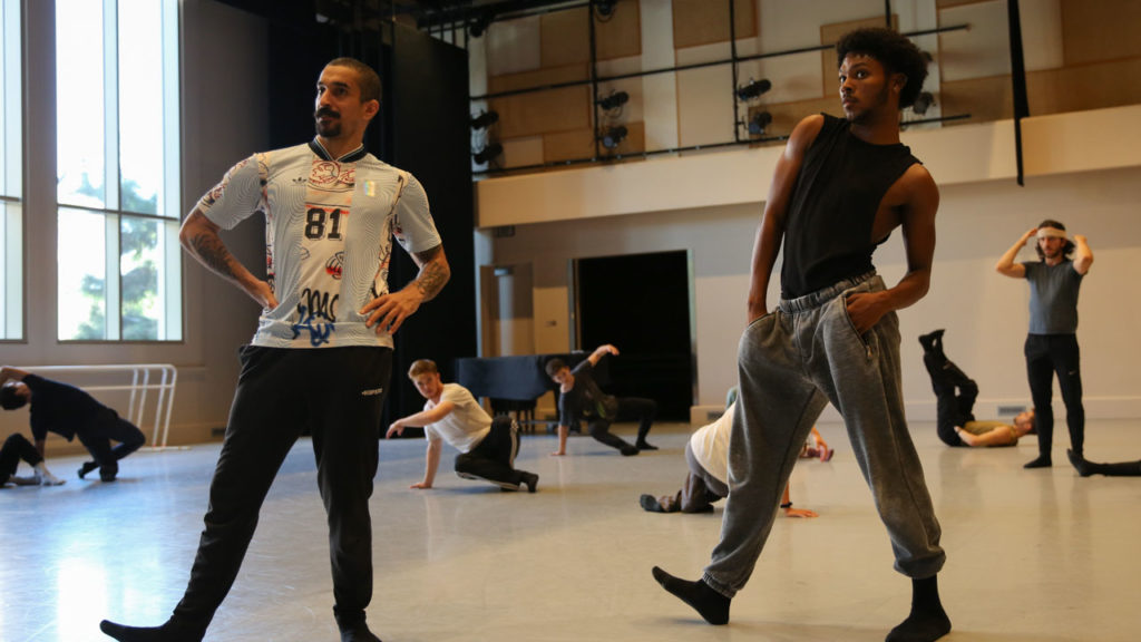 two dancers standing with hands on hips and right toes raised