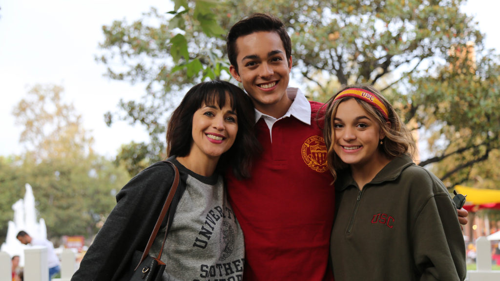 Zack Torres wearing cardinal polo smiling with mother and sister