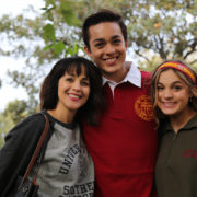 Zack Torres wearing cardinal polo smiling with mother and sister