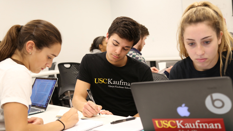 students writing and looking at a computer