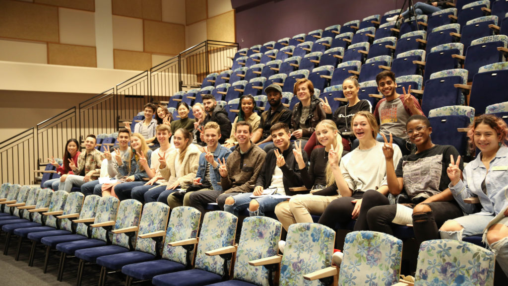 A group of students sit in the audience and give a "fight on"