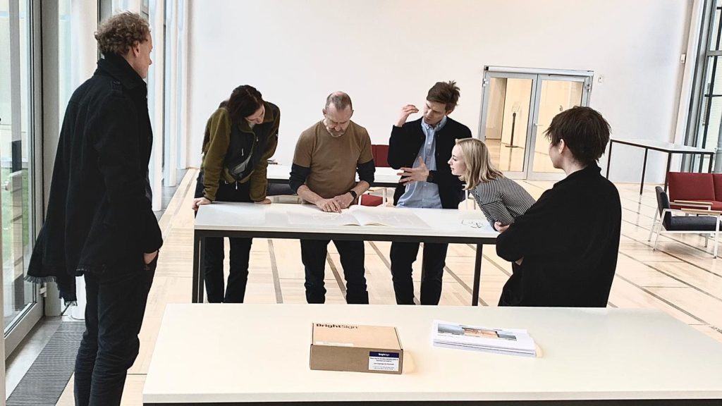 group of people look at papers on a table