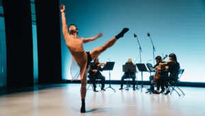 dancer on stage with leg up and musicians in the background