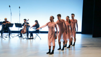 four dancers perform in front of seated musicians