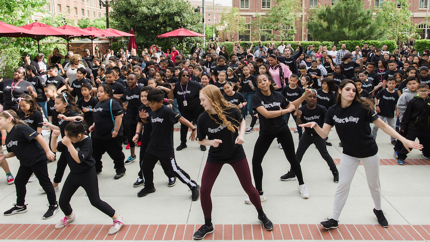 Older dancers leading young students outside