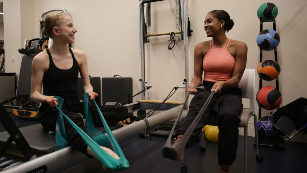 Two dancers use TheraBands in a fitness room