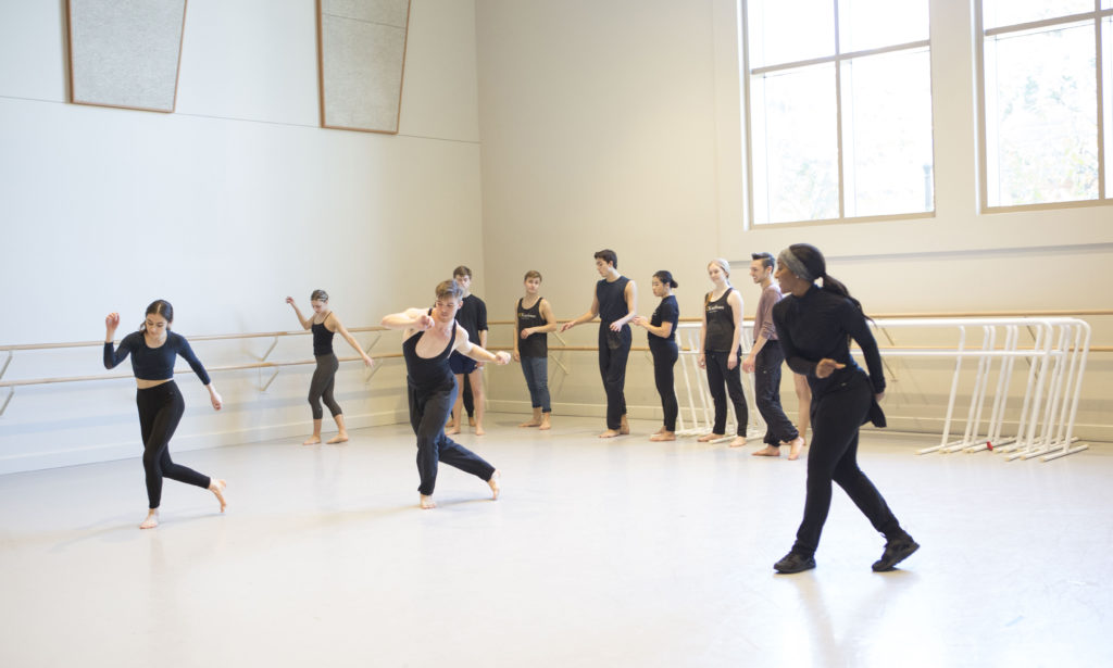 Students dance across the floor in a dance studio