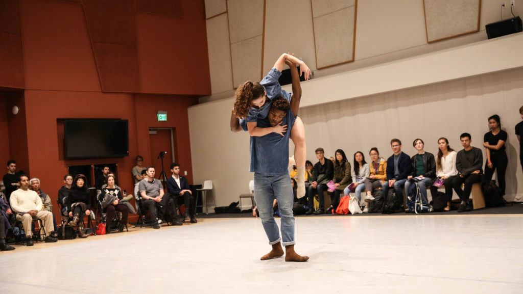 two dancers performing in a studio for a seated audience