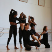 five dancers wearing black pose in a dance studio