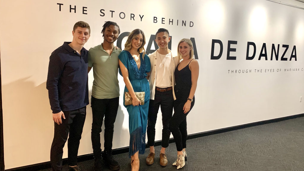 5 people pose in front of a wall that reads "The Story Behind Gala de Danza"