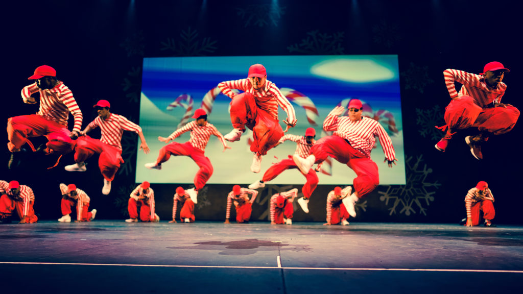 Dancers in red outfits jumping on stage