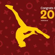 Gold silhouette of dancer doing a flip in front of festive cardinal background