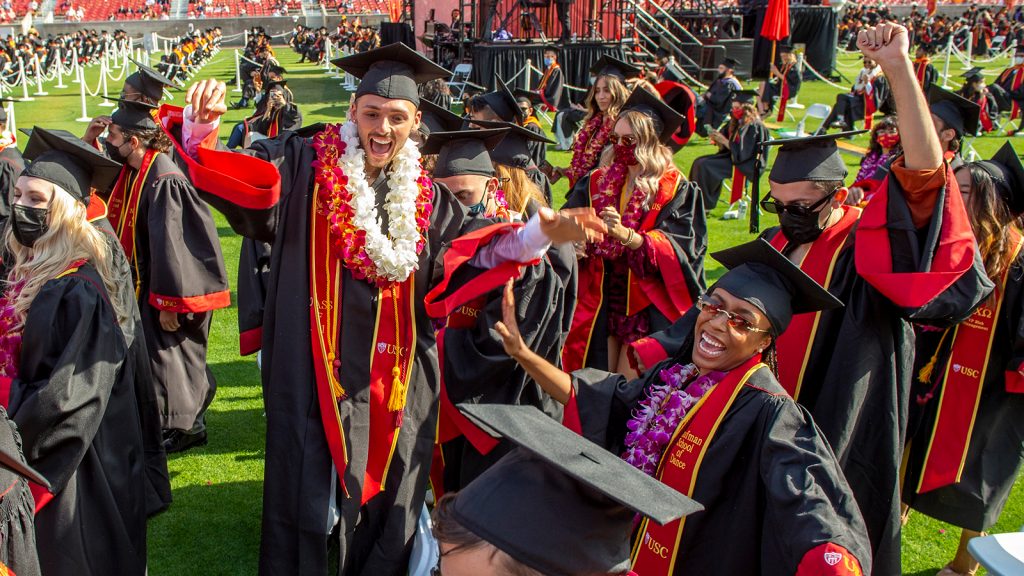 Students wearing caps and gowns smiling