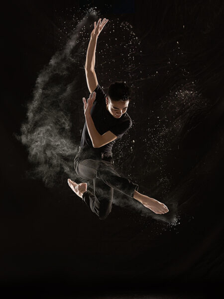 dancer jumping and crossing legs with dust flying.