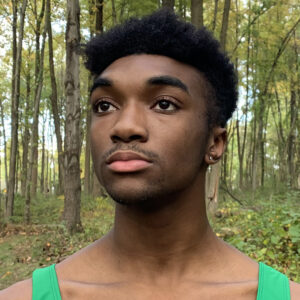 A person with short brown hair in a green tank top looking into the distance for a headshot
