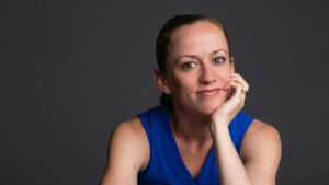 a person with their chin in hand smiling at camera for a headshot.